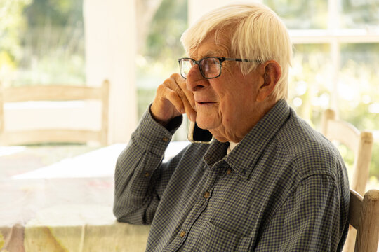 elderly man talking on cellphone at home