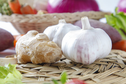 Fresh garlic and ginger with vegetables on woven basket