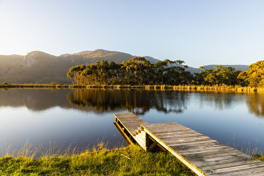 wooden launch overlooking placid pond at sunset, overlooking Klein Mountains, Stanford, South Africa