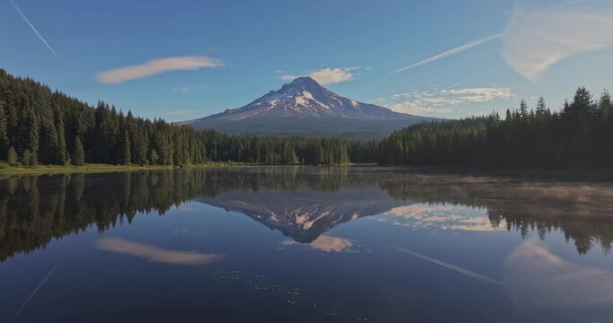 Aerial shot of a lake in the forest reflecting Mount Hood on the calm surface. Shot in Oregon, USA