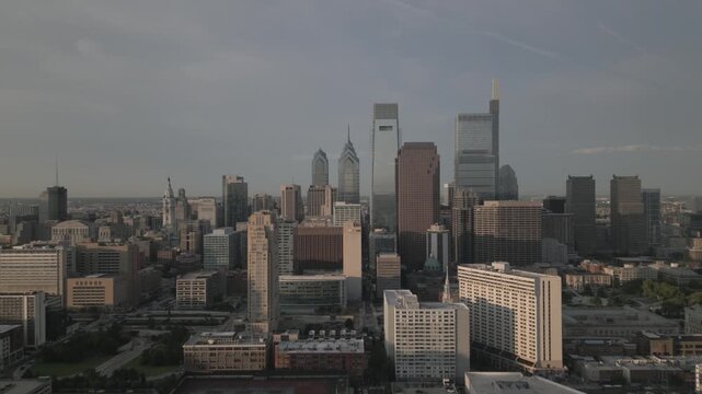 Aerial view of Philadelphia skyline during golden hour with skyscrapers and city streets in cinematic motion.