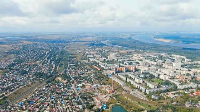 Volgograd, Russia. Aerial panoramic sweep over the Krasnoarmeisky district, revealing dense Soviet-era panel housing, the Volga-Don Canal corridor, and the broad Volga River under an overcast sky. Dr