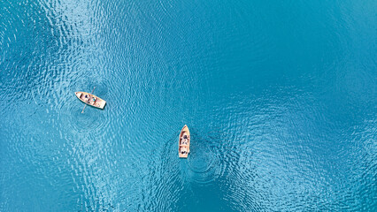 Two boats gently drifting on a tranquil turquoise lake under the sun with ripples creating patterns on the water's surface © Tetiana