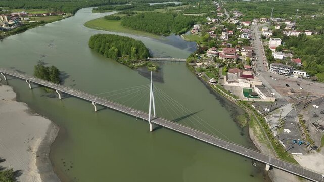 Aerial view of Anaklia resort in Georgia featuring the futuristic observation tower, pedestrian bridge over Enguri river, sandy beach, and Black Sea coastline on a sunny day.