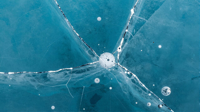 Cracked Blue Ice with Air Bubbles and Starburst Pattern on Frozen Lake