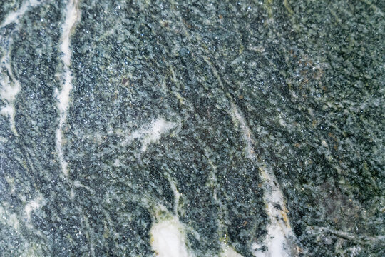 A collection of natural material samples is displayed in an organized composition featuring sintered stone, granite, and transparent glass textures. Each surface reveals unique veins, grains, reflecti