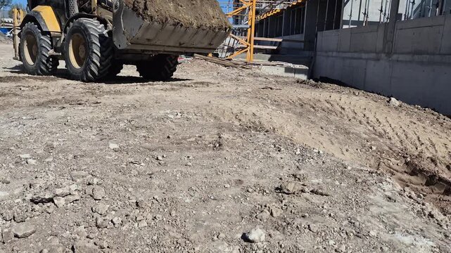 Large construction vehicle moving earth in front of foundation bottom view