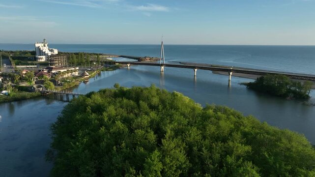 Aerial view of Anaklia resort in Georgia featuring the futuristic observation tower, pedestrian bridge over Enguri river, sandy beach, and Black Sea coastline on a sunny day.