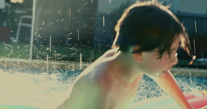 Wet boy climbing onto inflatable float with determined expression, hair dripping and body tense in backyard pool during golden hour summer evening