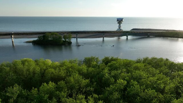 Aerial view of Anaklia resort in Georgia featuring the futuristic observation tower, pedestrian bridge over Enguri river, sandy beach, and Black Sea coastline on a sunny day.