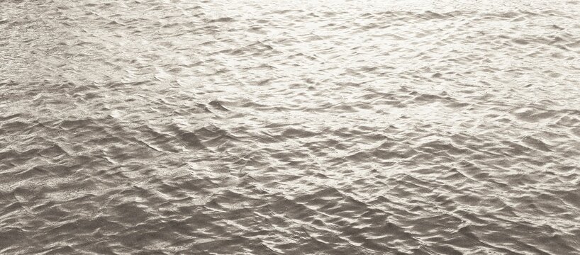 Minimalist photograph of shimmering water with gentle ripples and bright reflections. Clean, calm and versatile abstract nature texture.