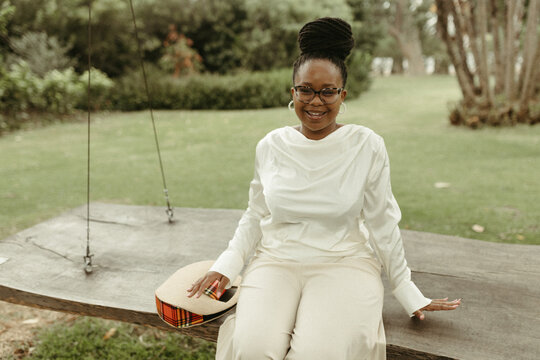 Smiling black woman relaxing on a large wooden swing