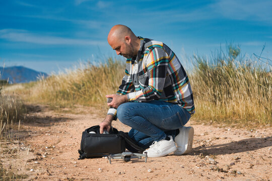 A man kneels, adjusting the drone for flight