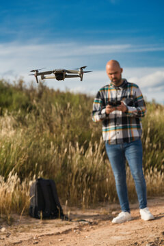 A man operates a drone outdoors with concentration