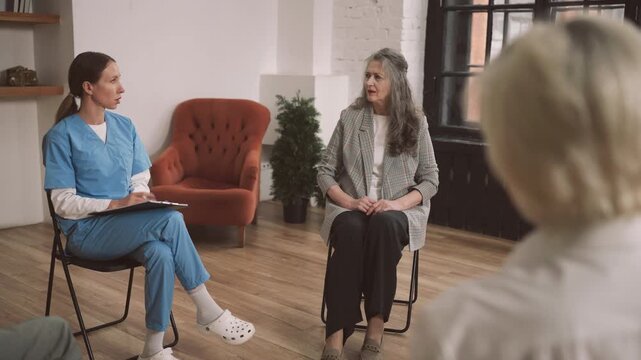 Professional psychologist communicating with group of aged woman, asks of aging. Beautician or endocrinologist speaking about modern treatments for save female beauty and health in old age, psychology