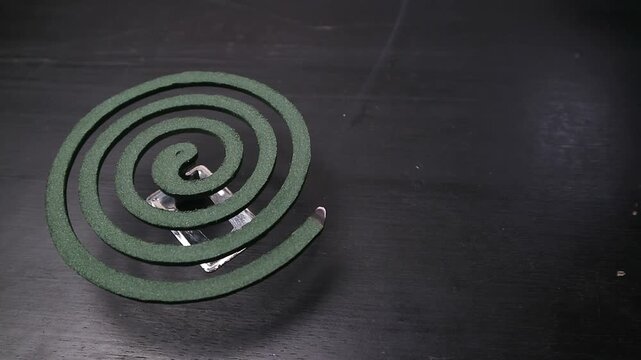 Burning Mosquito Repellent Coil Emitting Smoke on Dark Background