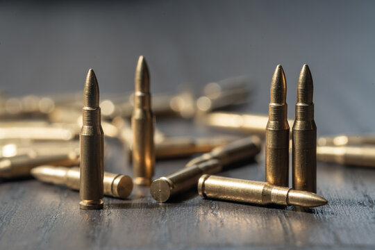 Bullets scattered on wooden table. Military ammunition, war and army concept.
