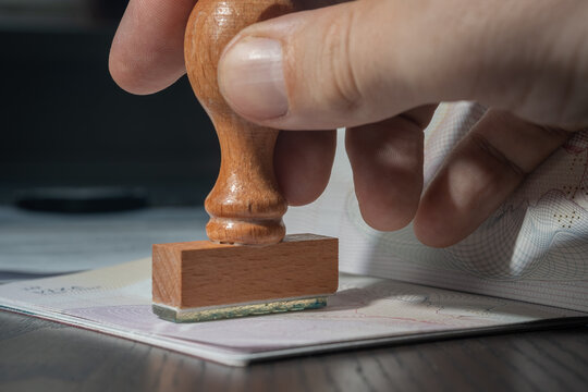 Man's hand is stamping a visa in passport. Close-up view.