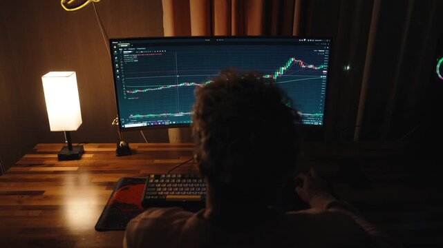 Professional trader or investor working at multiple monitors with stock market charts, financial data, and trading graphs.