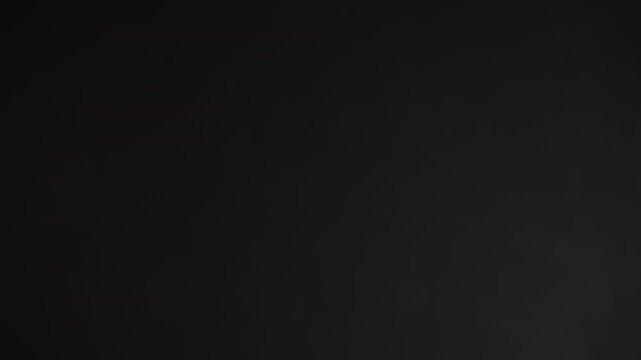 Slow motion real dust particles floating mid air over dark background
