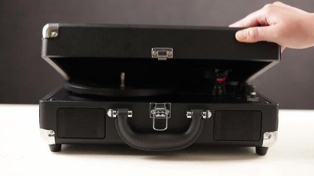 Retro portable record player opens to reveal turntable and speaker system