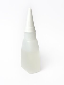 A clear plastic bottle with a white dispenser cap for storing and accurately applying superglue. Isolated on a white background for a home improvement and household chemicals concept.