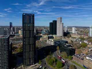 Obraz premium Red public buses at roundabout in Croydon aerial view. Modern architecture with tall skyscrapers in town center. Quiet roads in business district on a sunny day with blue sky.