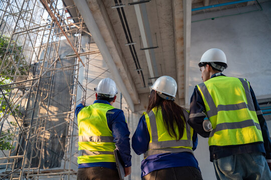 Construction engineering team inspecting scaffolding and building structure at active construction site