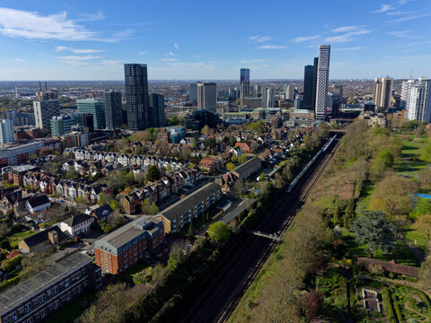 Croydon skyline on a sunny day aerial view. Railway tracks with trains arriving into Croydon town. Residential area opposite green public park. Business district in the center with modern skyscrapers.
