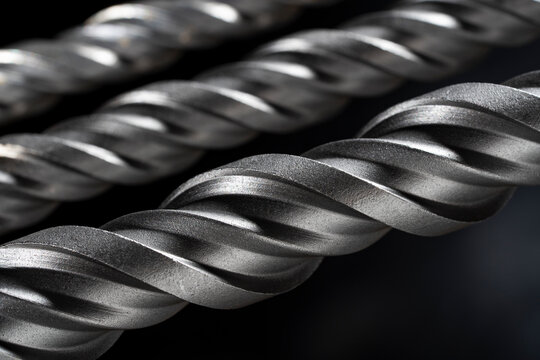 Macro steel spiral drill bit texture on dark background. Metal drill bit spiral flutes on black background. Concept of industrial tools engineering precision construction and hardware equipment