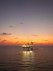Obraz premium Aerial View of Offshore Jack-Up Rig and Production Platform at Sunset. Offshore Energy Exploration and Production.