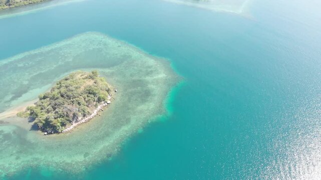 Panoramic aerial view of the 17 Islands Marine Park near Riung, Flores, Indonesia, featuring turquoise coral reefs, tropical islets, and deep blue ocean under a bright sky