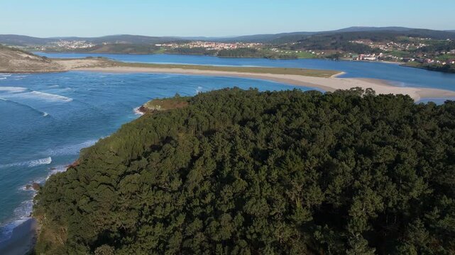 Coastal Estuary Landscape With Dense Forest In Foreground And Sandy Beach In Galicia, Spain. wide aerial shot