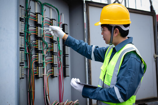 Engineer inspects terminal wiring inside an electrical cabinet at a substation, supporting diagnostics, maintenance testing, safety compliance, and grid reliability.