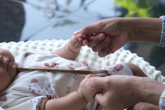 A mother plays with her baby. their hands held each other gently. Immortalize love, protection and new life in a loving embrace.
