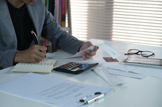 Financial concept, young business woman hand holding bill, write management budget for saving costs, finance planning to spend enough money on her income to save money, paying tax, investing.
