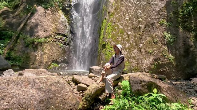 Asian woman vacation at Dolo waterfall. One of beautiful waterfall in East Java, Indonesia.