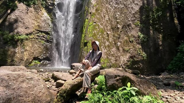 Asian woman vacation at Dolo waterfall. One of beautiful waterfall in East Java, Indonesia.