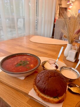 Bowl of traditional Eastern European beet soup borscht served hot with sour cream and fresh bread, featuring cabbage potatoes carrots onions, rich red broth and Ukrainian heritage flavor profile dish.