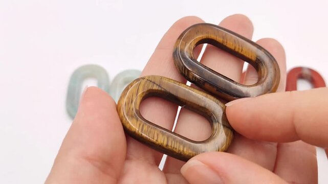 Two smooth tigers eye quartz links are held in hand, showing their rich golden brown bands and chatoyant light reflections perfect for custom artisan jewelry supply designs