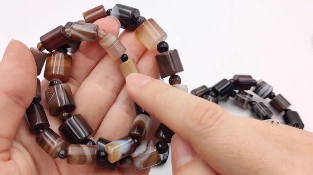 Various natural banded agate jewelry items against a clean white background including cylindrical bead bracelets and polished rectangular pendants showing distinctive stripes