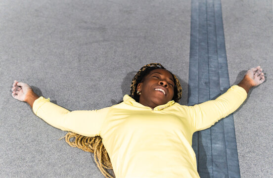 Exhausted woman resting on climbing gym crash pad