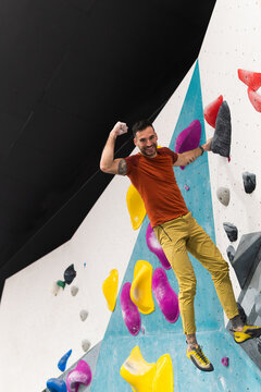 Man smiling flexing arm bouldering in climbing gym