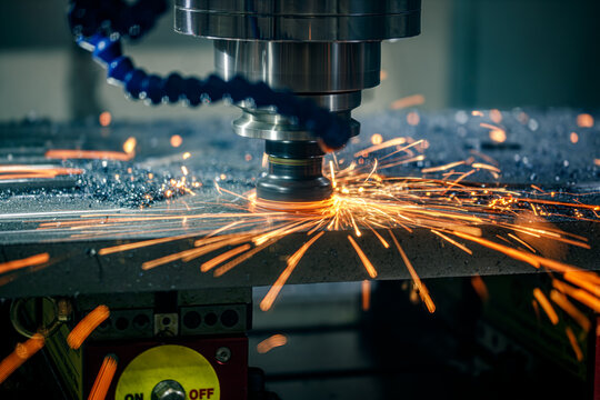 CNC milling cutter cutting metal with bright sparks in factory.
