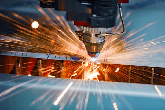Industrial CNC laser cutting machine with flying sparks in metal fabrication.