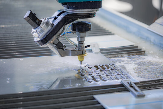 CNC waterjet cutting machine processing metal sheet in factory.