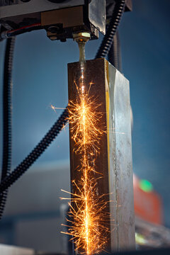 Wire EDM cutting of metal workpiece with sparks in industrial machine.