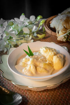 Traditional Thai sweet sticky rice with durian and coconut milk cream served in a glass bowl decorated with fresh orchid flowers and pandan leaves, top view overhead shot for Asian food concept.