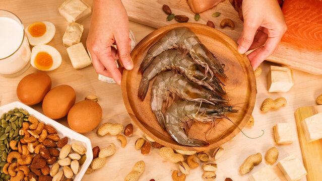 Hands Holding Wooden Plate of Fresh Raw Shrimp with Protein Foods