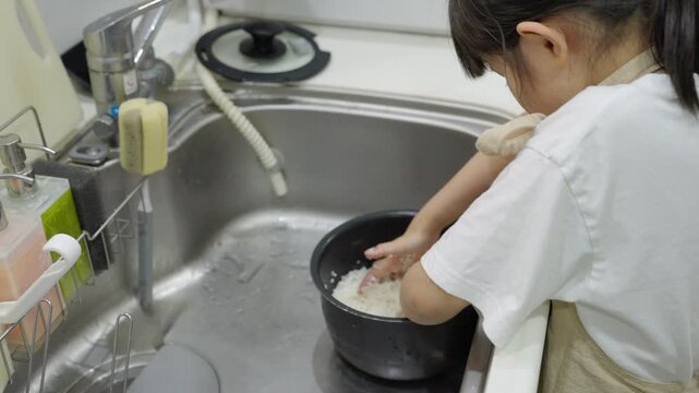 料理のお手伝いでお米を研ぐ子供